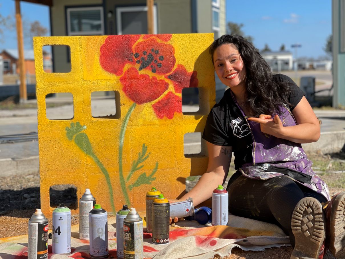 Woman artiest setting in front of a mural