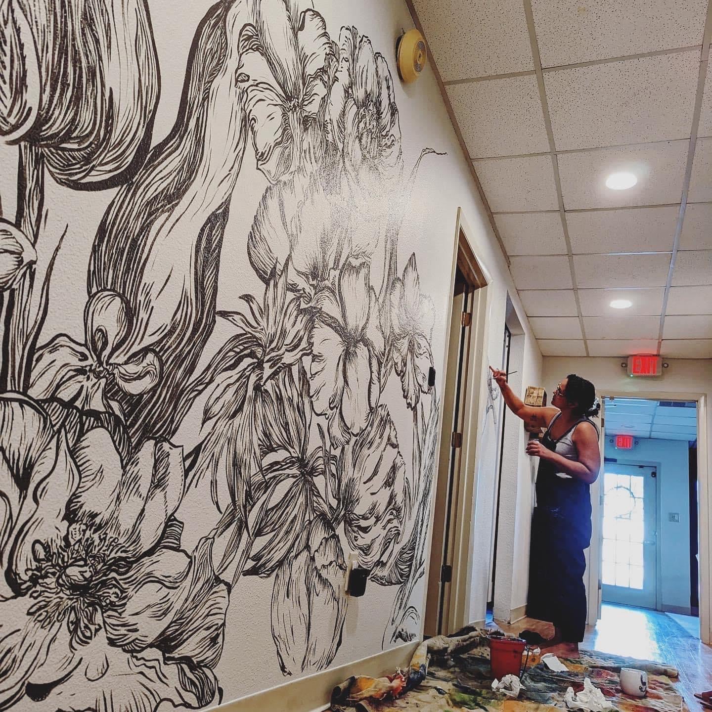 Woman painting a logo mural for a business