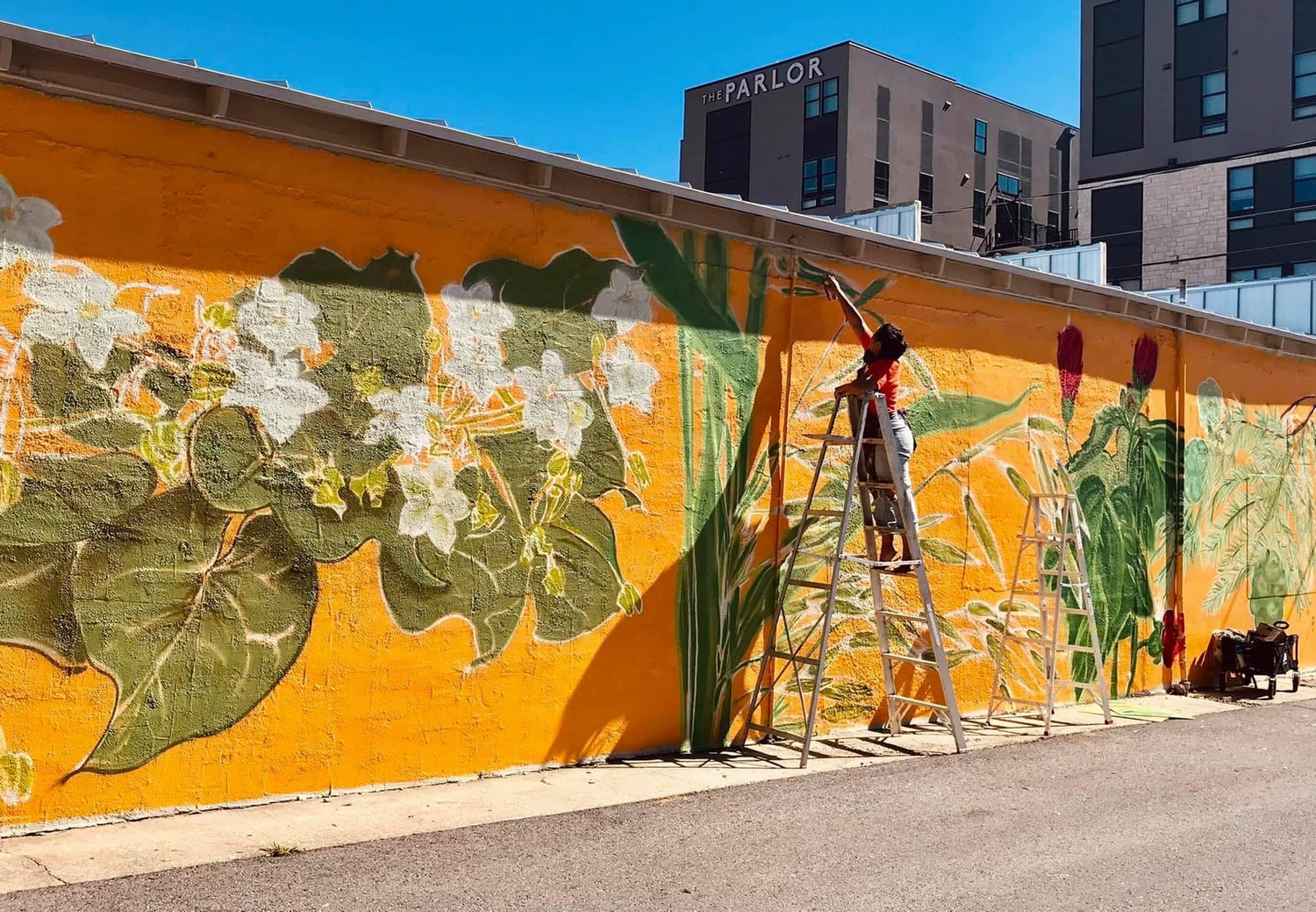 Woman painting a mural on the outside of a business. 