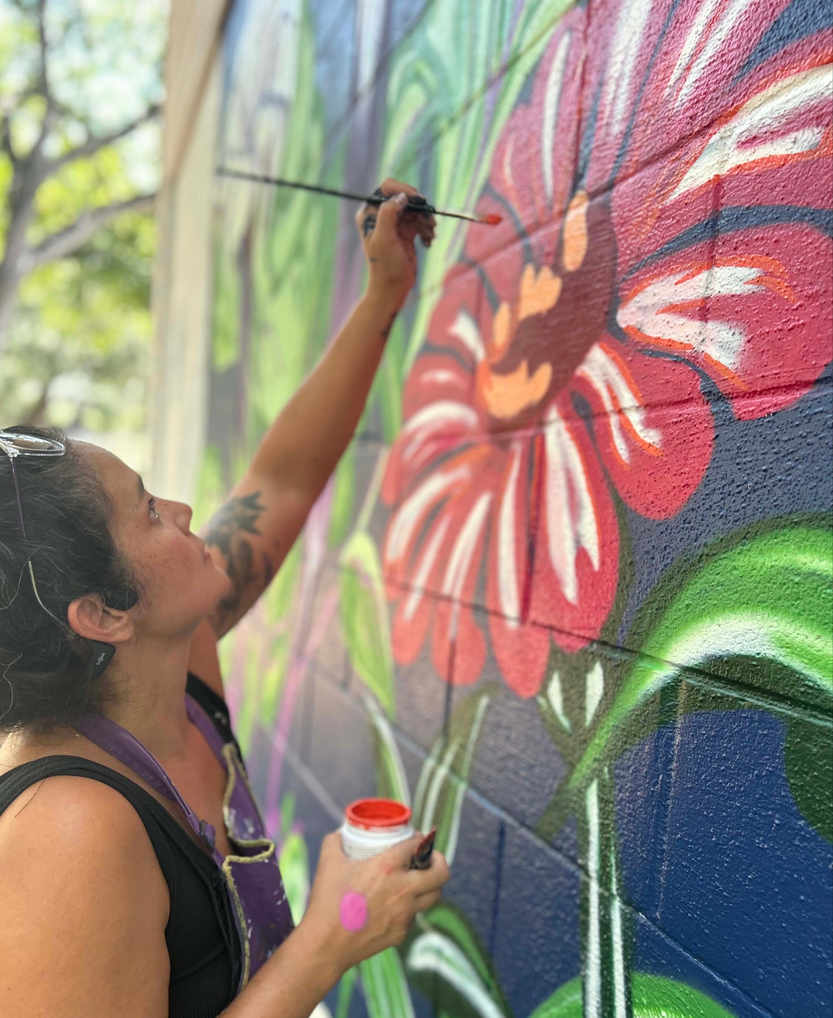 woman painting a flower mural